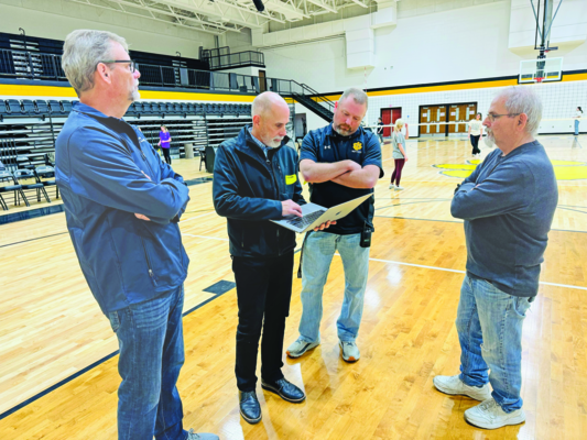 Historical Society President Mike White (left) looks at the gym wall as Tom Kraemer of Kraemer Design shows Athletic Director Tommy Nicholson the artist rendering planned for the space.  Photo by Mark Hoskins